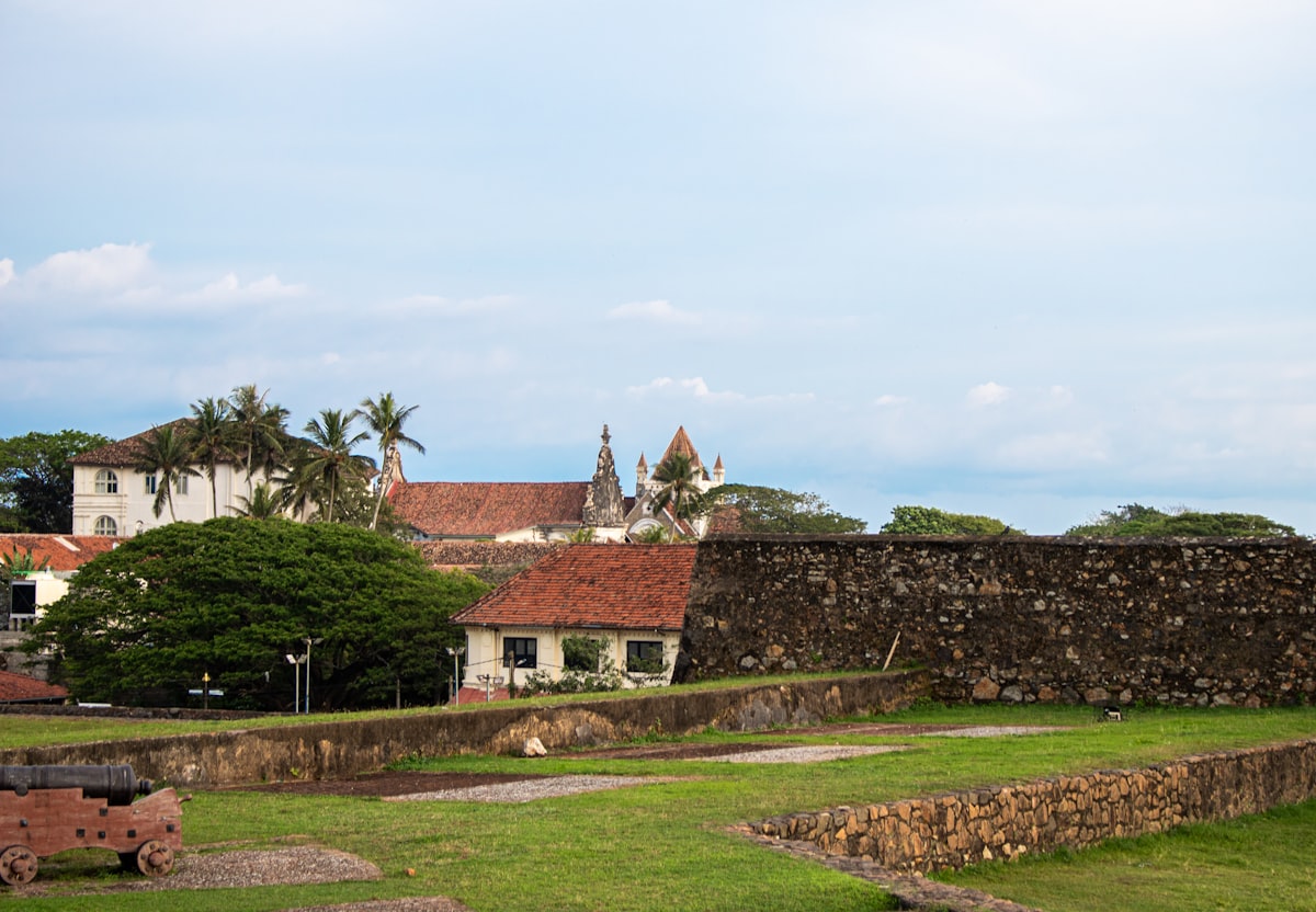 Fort walls and colonial buildings with an old cannon in the foreground
