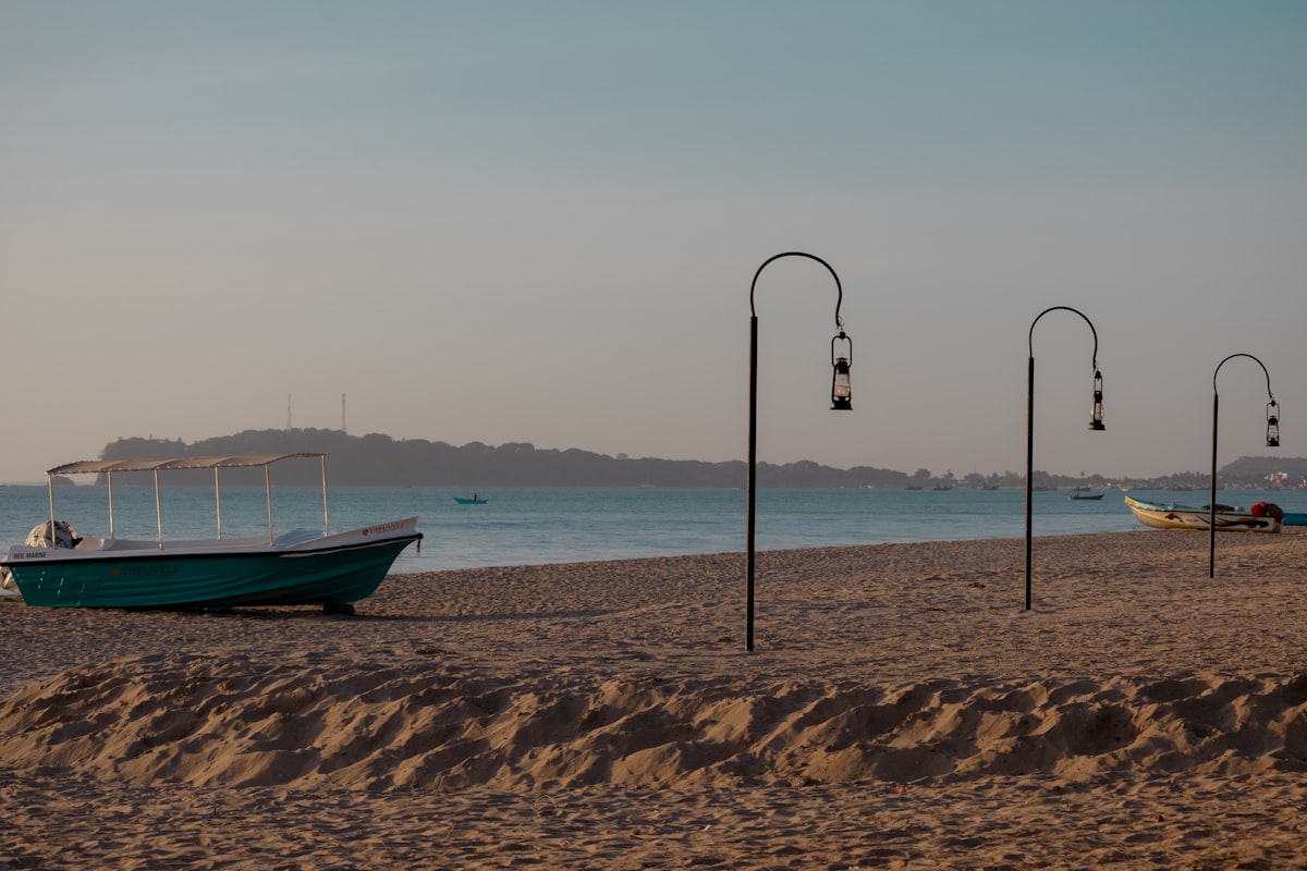 Turquoise waters and white sand of Nilaveli Beach stretching into the distance with Pigeon Island visible offshore